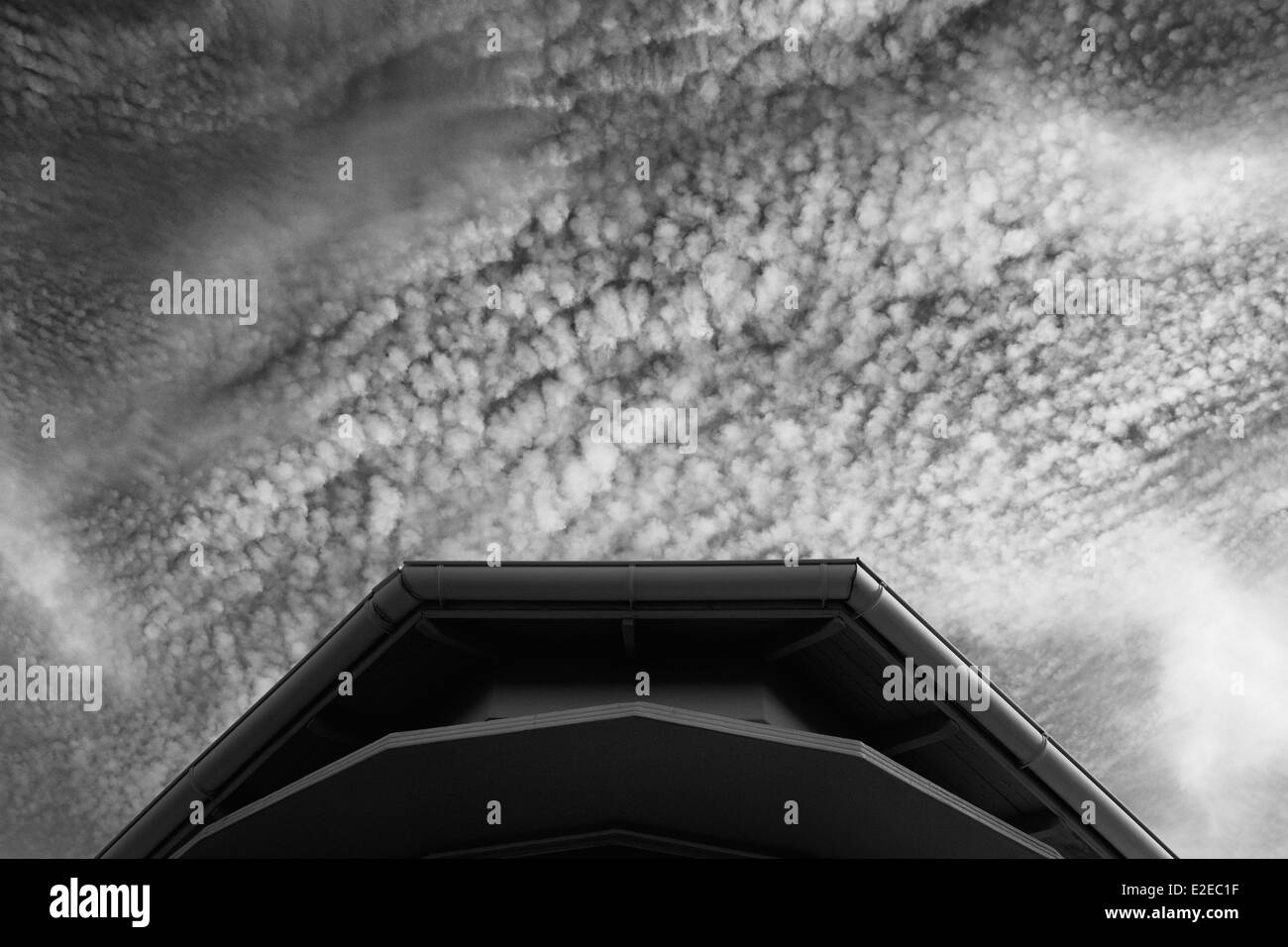 Fotografia in bianco e nero del tetto di casa con cielo molto nuvoloso in background. Foto Stock