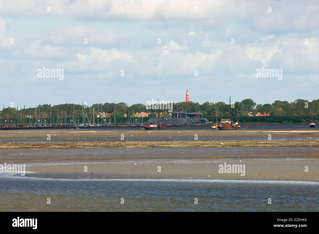 La bassa marea nel mare di Wadden in vista di un faro e il porto dell'isola di Schiermonnikoog nei Paesi Bassi Foto Stock