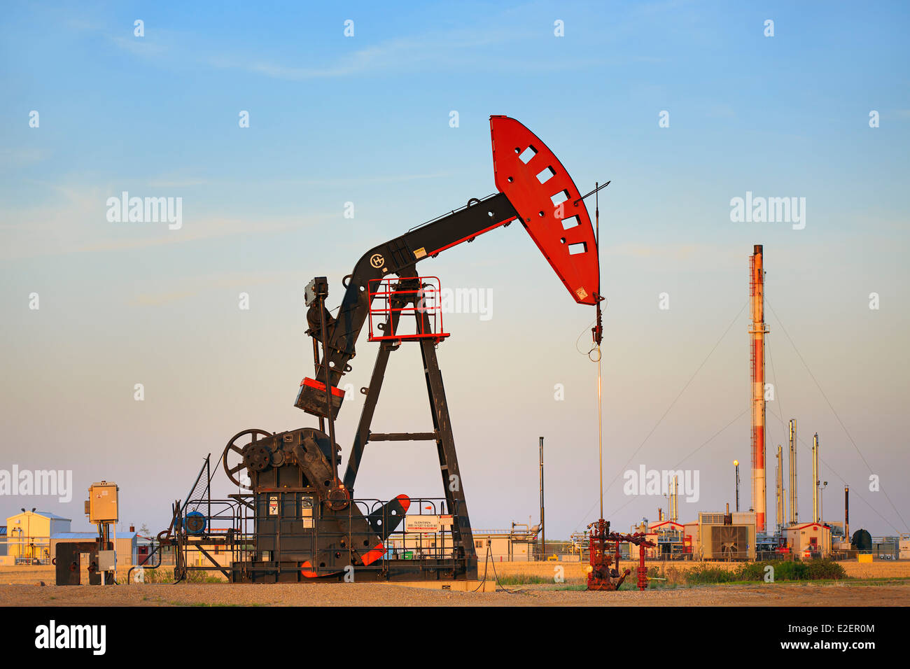 Olio pompa bene jack, con gas naturale liquido impianto in background, vicino Estevan, Saskatchewan, Canada Foto Stock