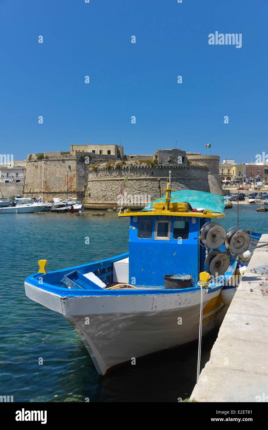 Italia Puglia Provincia di Lecce Gallipoli blu barca da pesca a fianco della banchina con il castello-fortezza Aragonais del XV secolo Foto Stock
