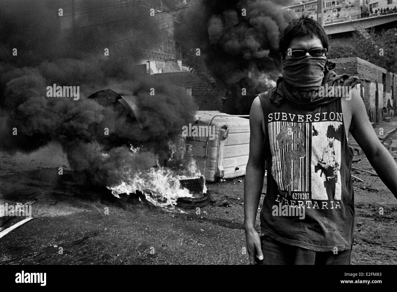 Uno studente cileno si erge di fronte alla masterizzazione di barricata durante il governo anti-protesta a Valparaíso, Cile. Foto Stock