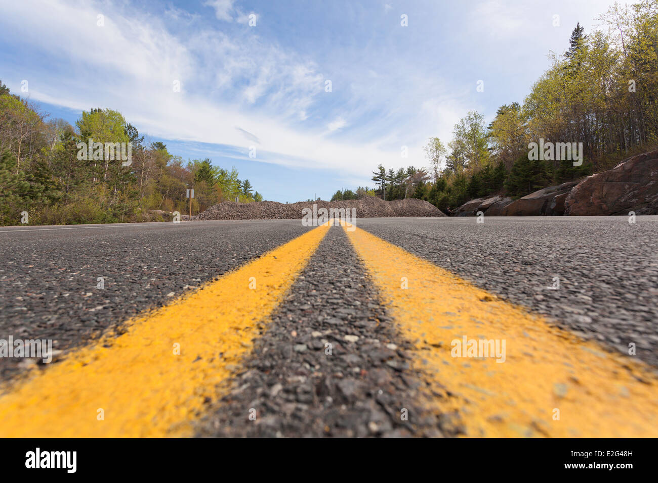Due solide su strada le linee di marcatura presi da un angolo basso con una pietra temporaneo blocco stradale su Murdock River Road vicino a Sudbury Ontario Foto Stock