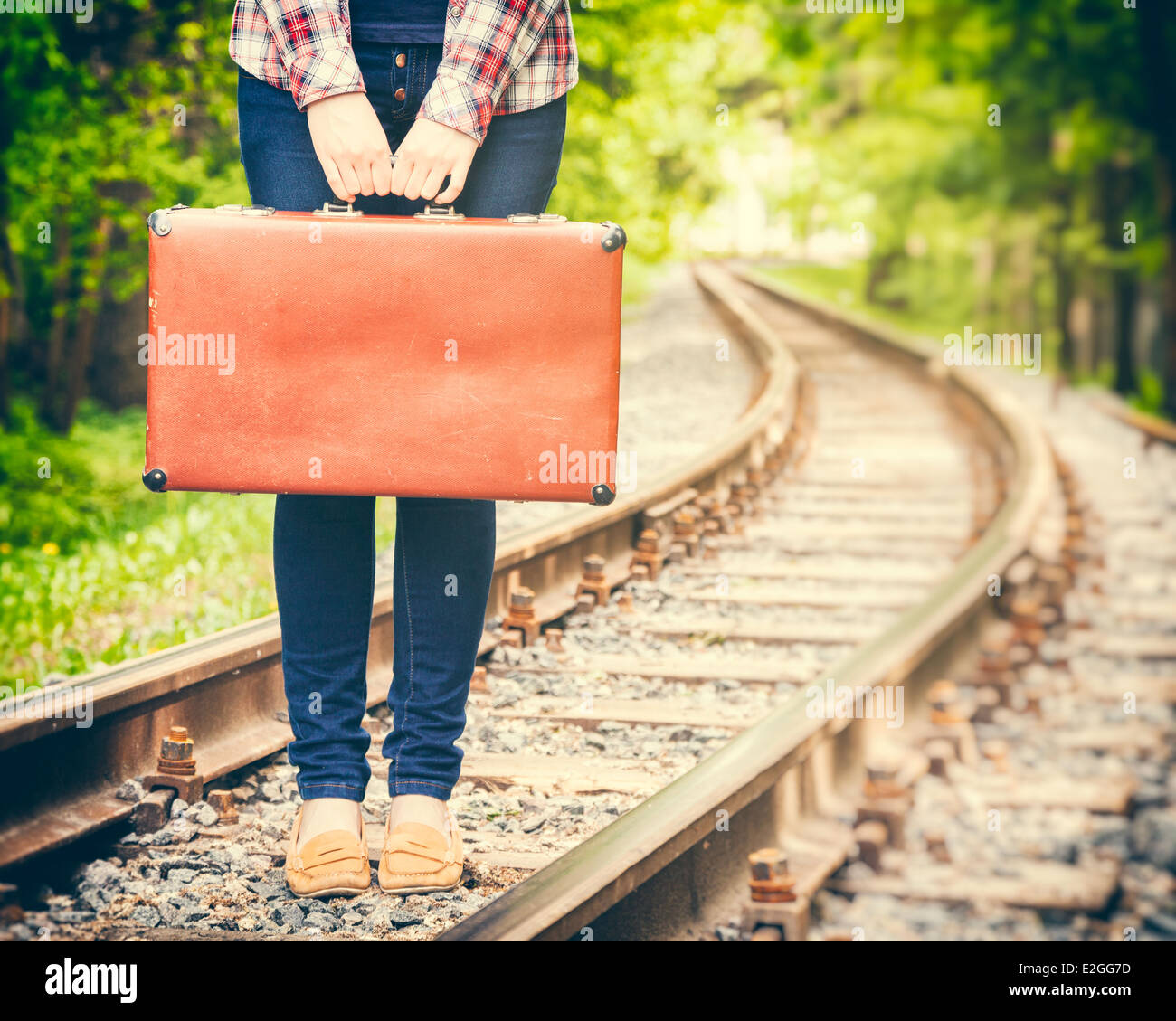 Ragazza con retro vintage valigia su ferrovia e stilizzato rétro Foto Stock