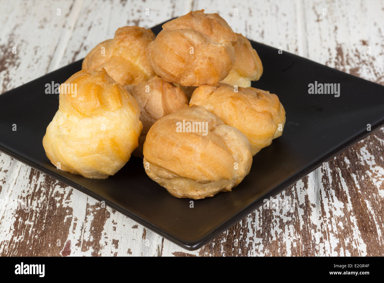 Eclair su nero piastra ceramica su uno sfondo di legno Foto Stock