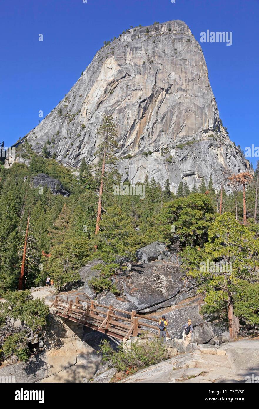 Stati Uniti California Sierra Nevada Parco Nazionale Yosemite elencati come patrimonio mondiale dall' UNESCO Yosemite Valley gli escursionisti a piedi ponte che attraversa il fiume Merced sul sentiero di Nevada Fall Liberty Cap cupola di granito in background Foto Stock