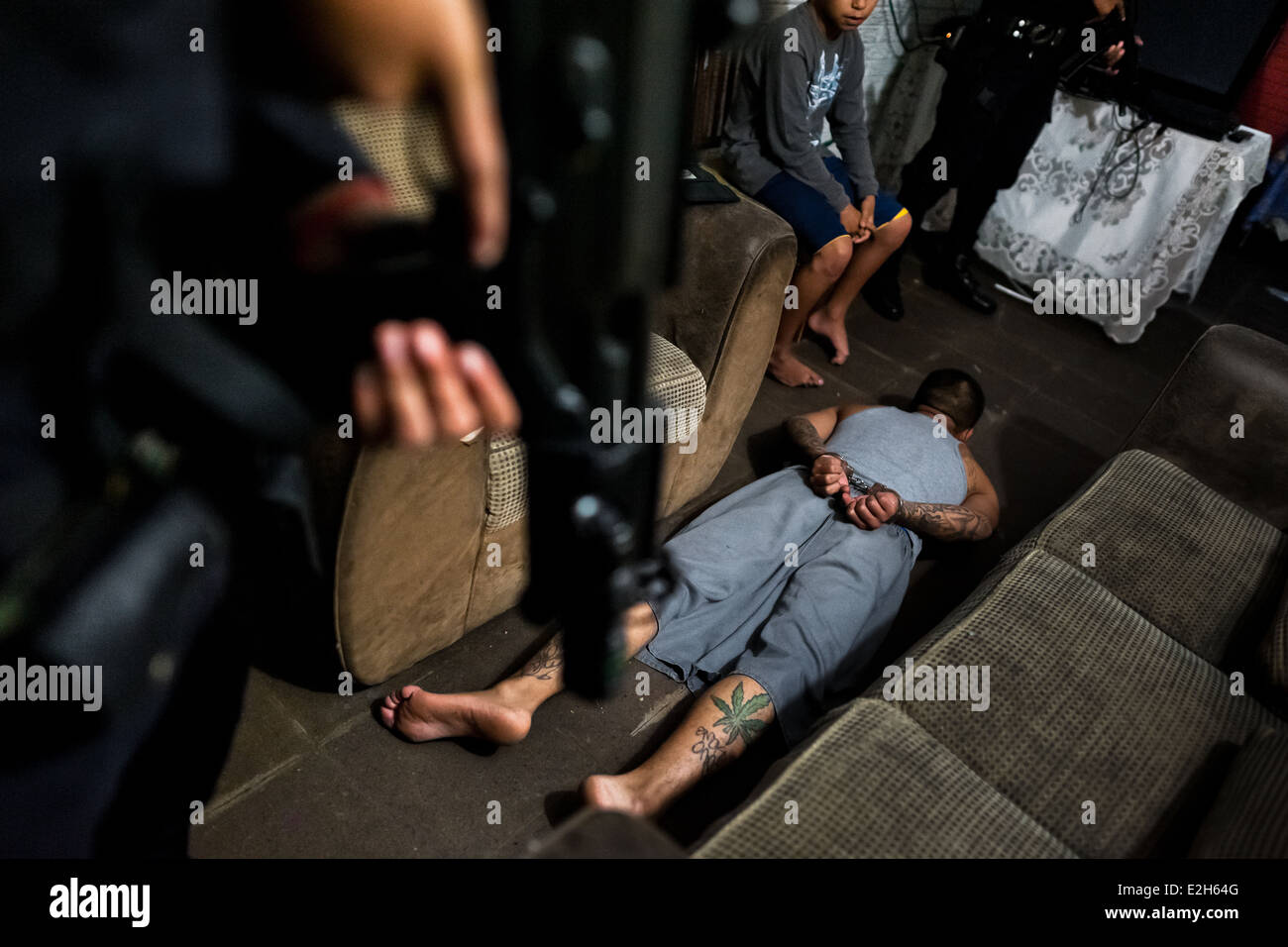 Un presunto membro della gang giace sul pavimento durante una notte in raid Soyapango, una pista quartiere di San Salvador El Salvador. Foto Stock