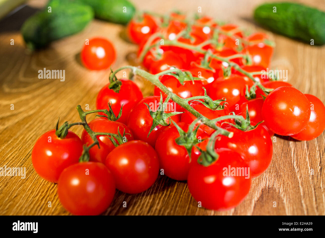 Pomodori ciliegia su un ramo. Nei pressi di cetrioli e ortaggi. Foto Stock