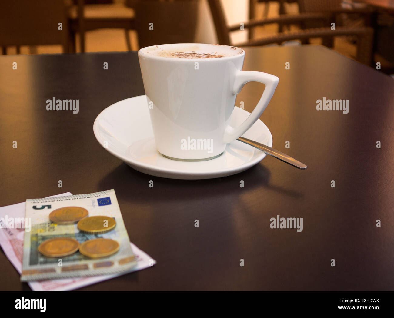 Tazza di caffè e qualche euro, su un tavolo del bar. Foto Stock
