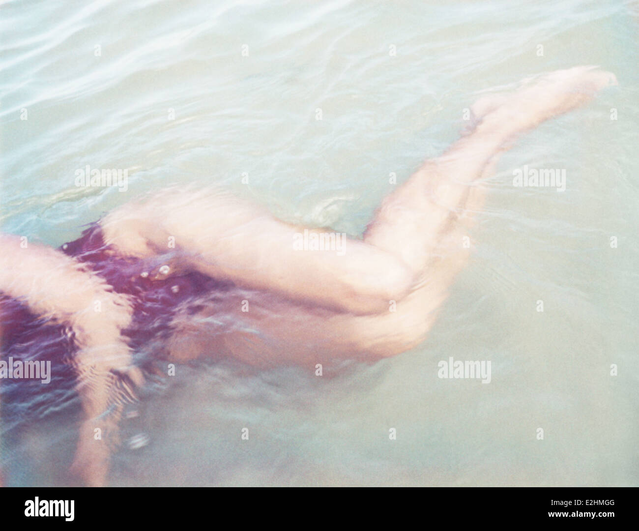 Donna sdraiata su lato in acque poco profonde, vista ritagliata Foto Stock