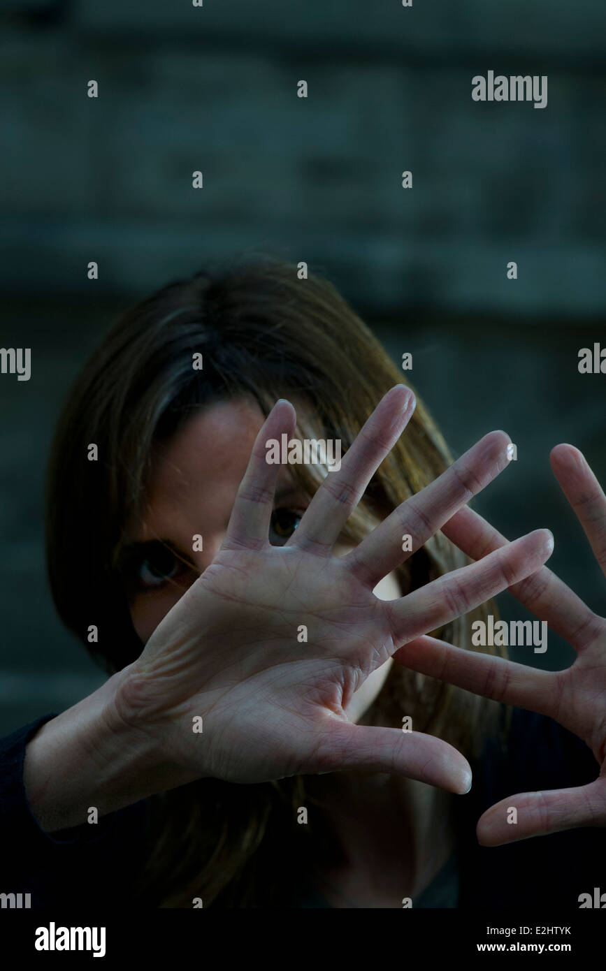 La donna alzando le mani per scongiurare un attacco Foto Stock
