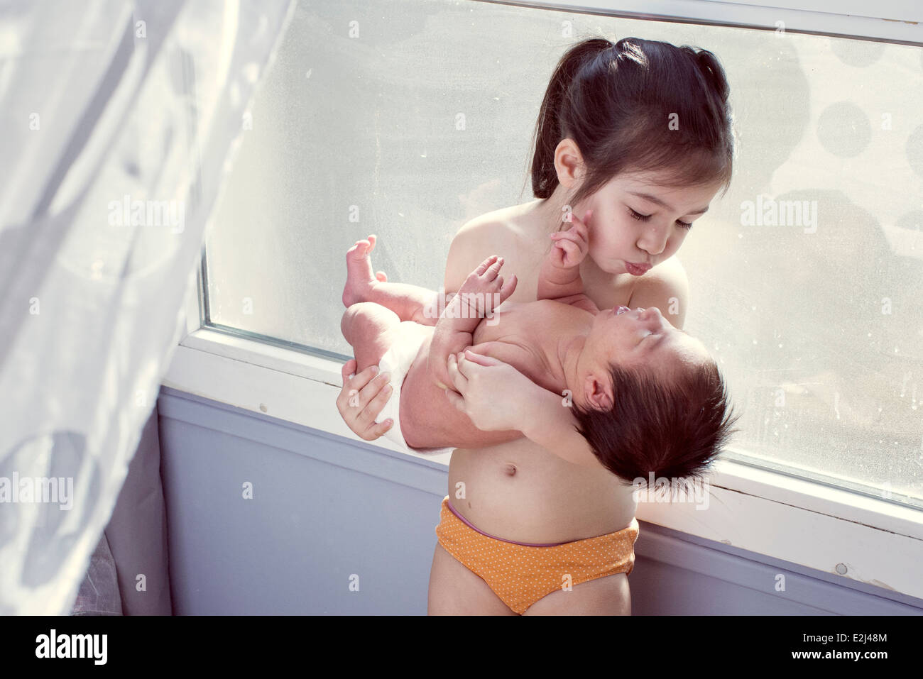 Little Girl holding baby Foto Stock