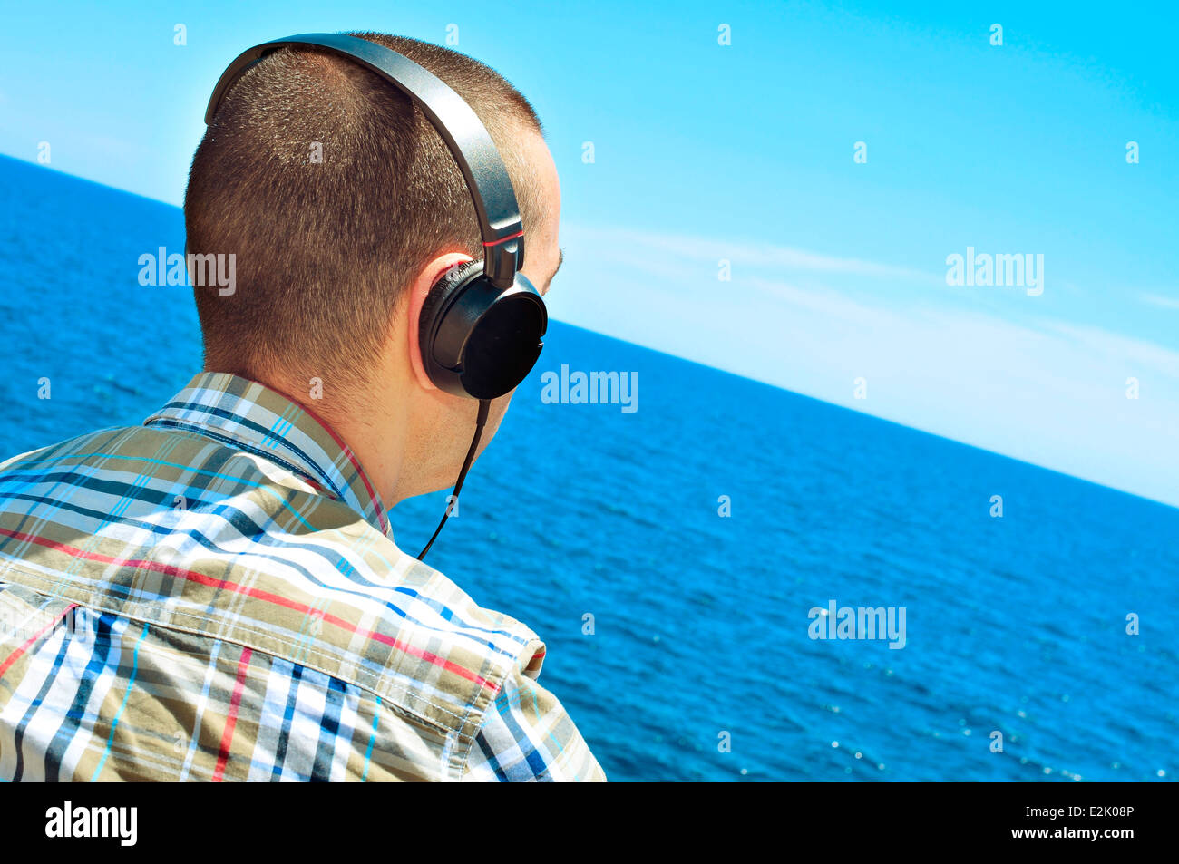 Un giovane uomo che ascolta musica con le cuffie nella parte anteriore di mare Foto Stock