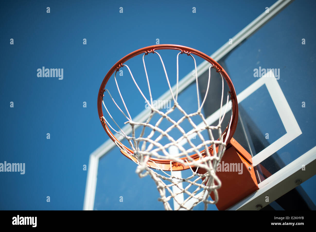 Un arancione Basketball hoop con una cornice trasparente con net contro un cielo blu chiaro. Foto Stock