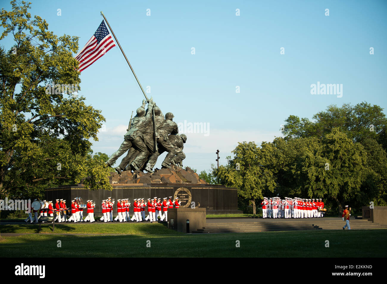 Marine Corps War Memorial Sunset Parade Arlington Virginia // ARLINGTON, Virginia - membri del corpo dei Marine degli Stati Uniti Drum e Bugle Corps, "The Commandant's Own", si esibiscono durante la Sunset Parade al Marine Corps War Memorial. L'unità musicale d'élite, fondata nel 1934, esegue movimenti di precisione mentre suona musica marziale tradizionale. L'iconico memoriale, raffigurante la bandiera che si innalza a Iwo Jima, funge da sfondo drammatico per queste cerimonie estive settimanali che si tengono il martedì sera. Le esibizioni mostrano la precisione del corpo dei Marines e lo sfarzo militare per il pubblico di ma Foto Stock