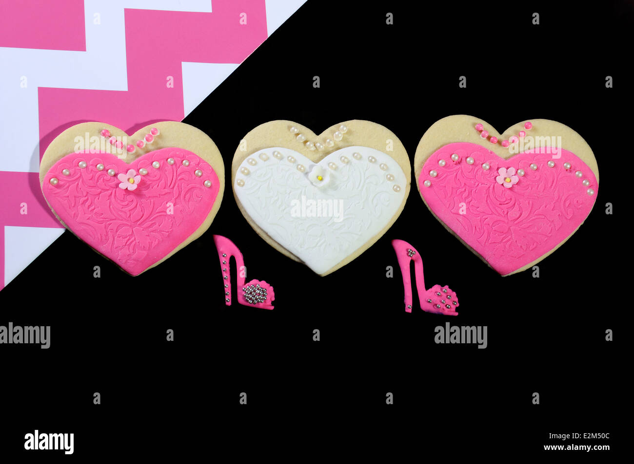 Sposa e le sue damigelle hanno colore rosa e bianco cuore wedding cookies sul chic nero e sfondo rosa. Foto Stock