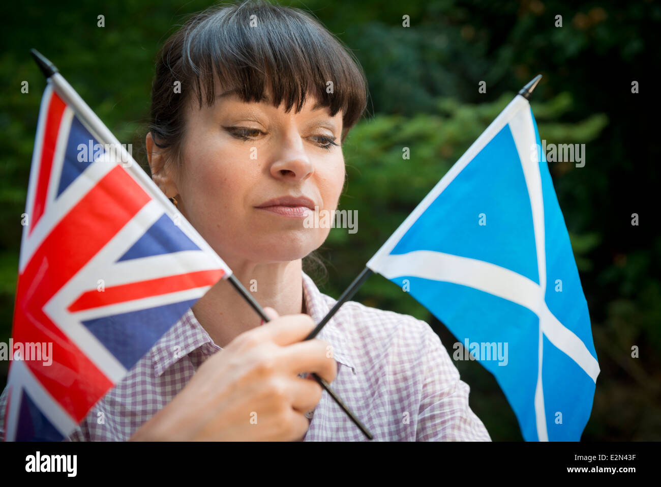 Giovane donna guardando un scozzese e la bandiera britannica di decidere come votare in scozzese referendum di indipendenza Foto Stock