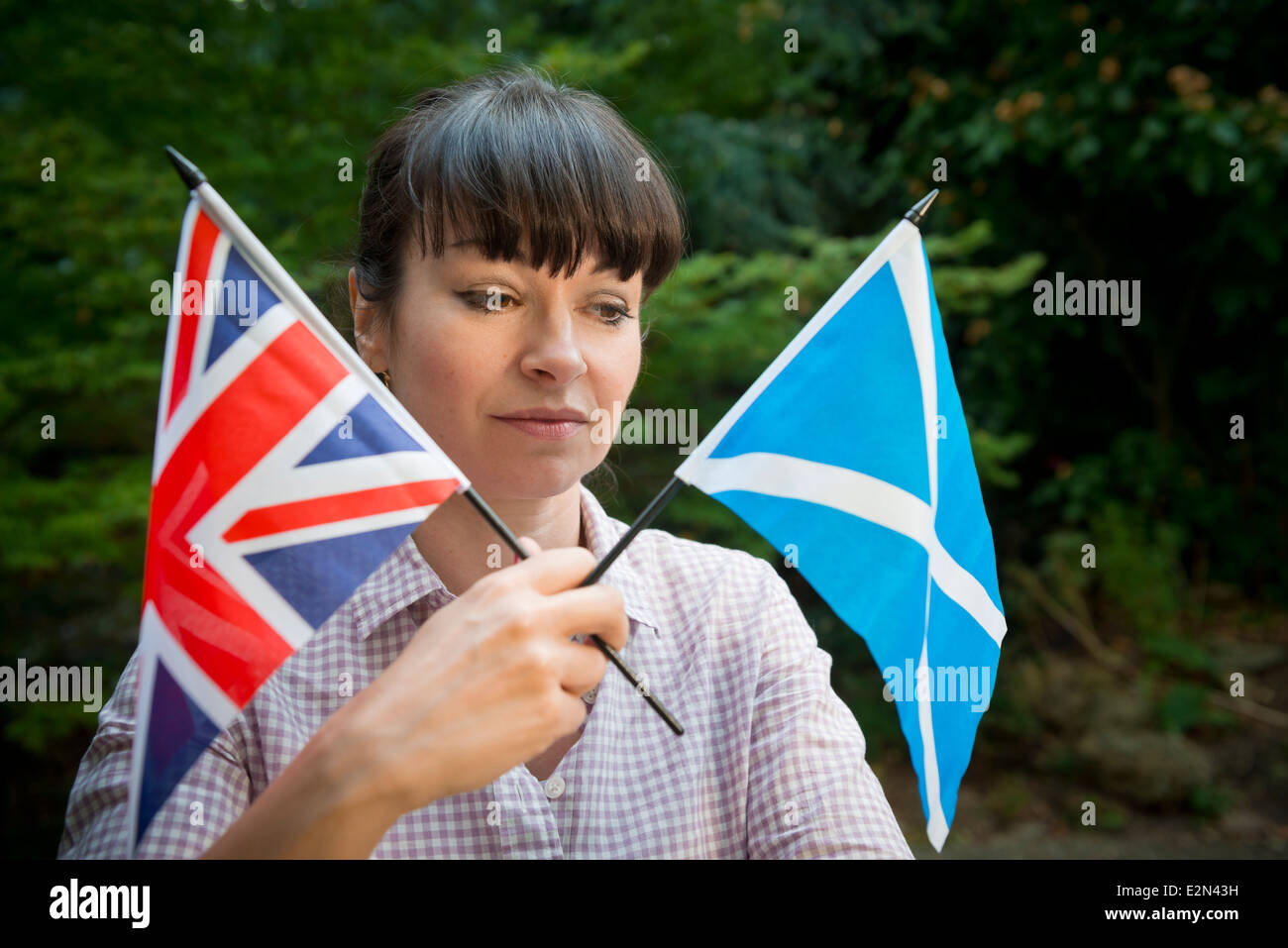 Giovane donna guardando un scozzese e la bandiera britannica di decidere come votare in scozzese referendum di indipendenza Foto Stock
