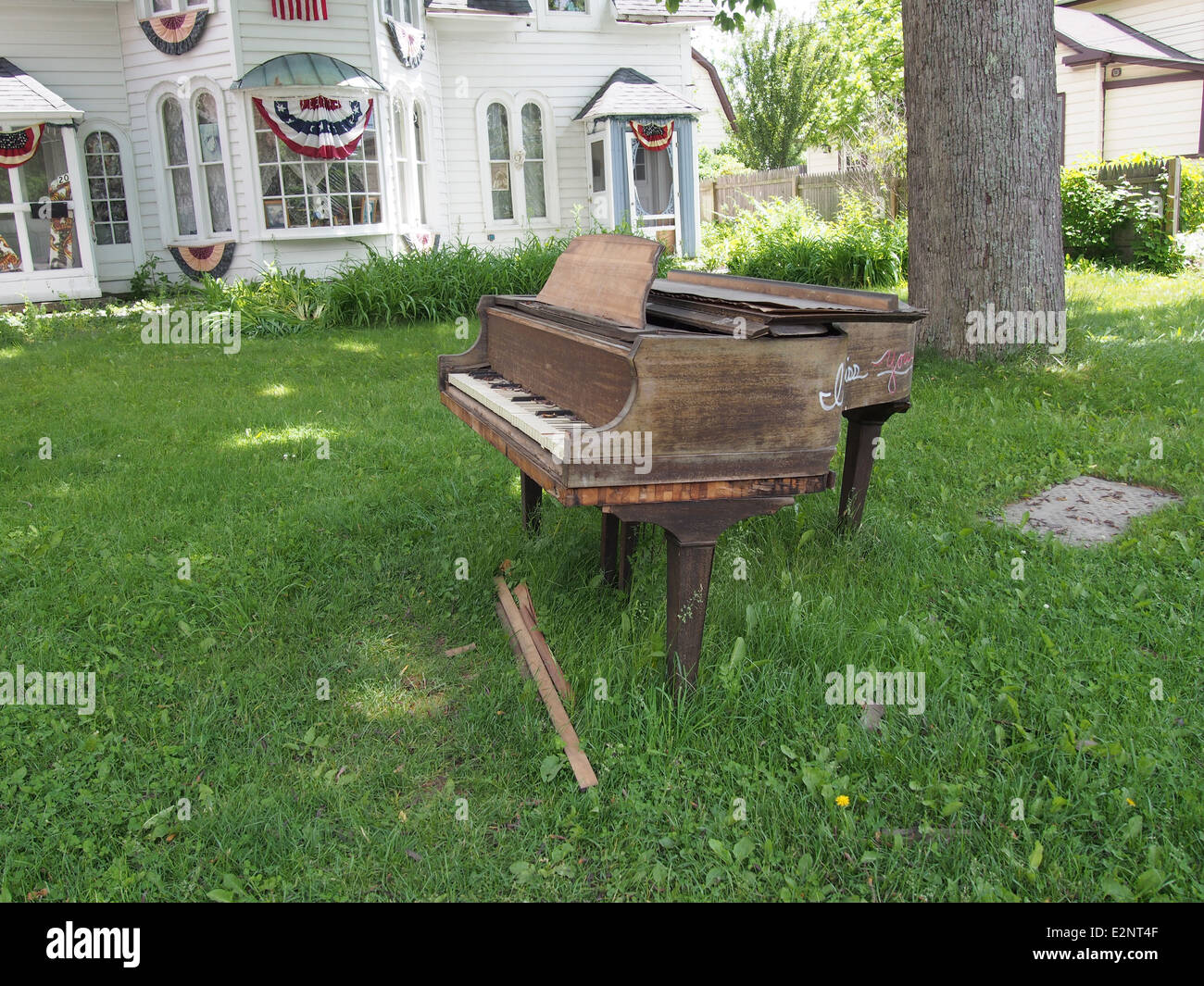 Rotto il vecchio pianoforte è lasciato per il cestino su un cortile anteriore prato di Woodstock, New York, USA, Giugno 7, 2014 © Katharine Andriotis Foto Stock