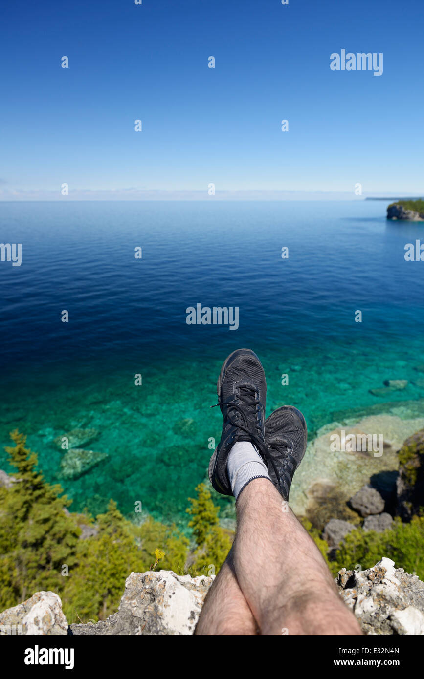 Le gambe di una persona seduta su una scogliera sopra Georgian Bay, il Lago Huron a Bruce Peninsula National Park, Ontario, Canada Foto Stock