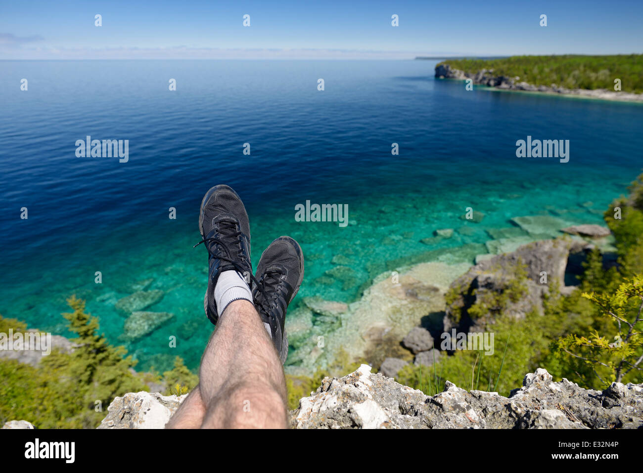 Le gambe di una persona seduta su una rupe di Georgian Bay, il Lago Huron a Bruce Peninsula National Park, Ontario, Canada Foto Stock