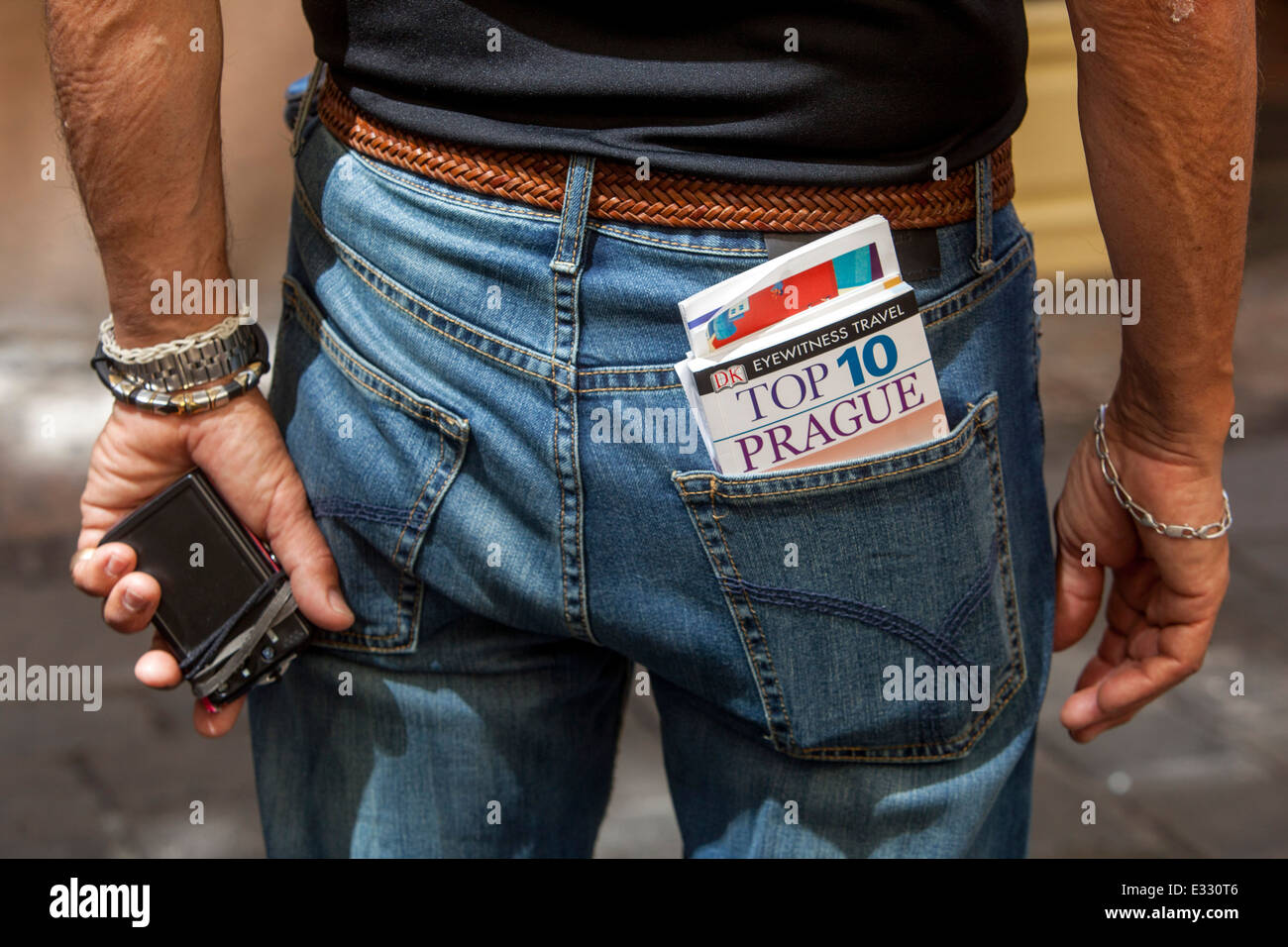 Guida cartacea uomo con Praga tascabile testimone oculare Repubblica Ceca Libro di viaggio nella tasca posteriore dei jeans Foto Stock