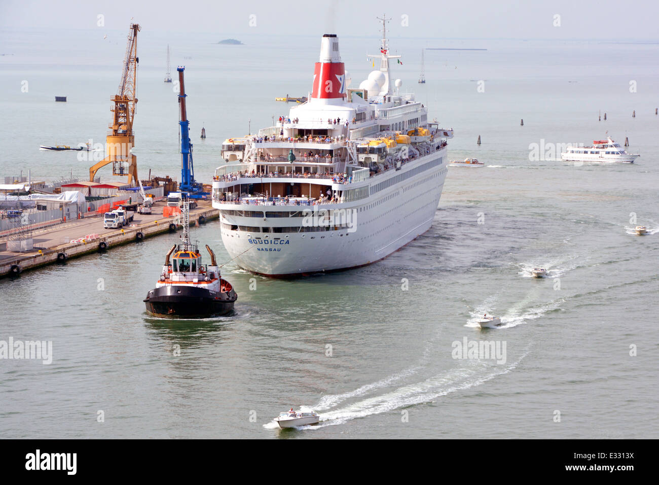 I passeggeri sul ponte della nave da crociera Fred Olsen Lines Boudicca sono trainati a ritroso in rimorchiatore fino alla nascita per la visita estiva al Porto di Venezia Italia Foto Stock
