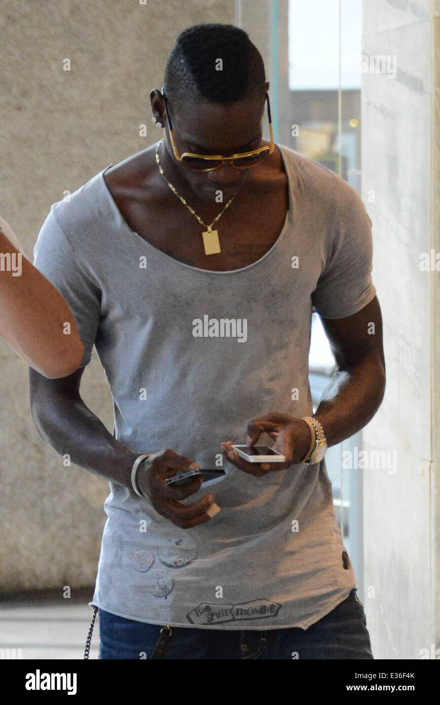 Il calcio italiano star Mario Balotelli e un amico tornare alla loro  Ferrari dopo una breve visita a un negozio Louis Vuitton a Milano.  Balotelli può essere osservata usando due telefoni cellulari