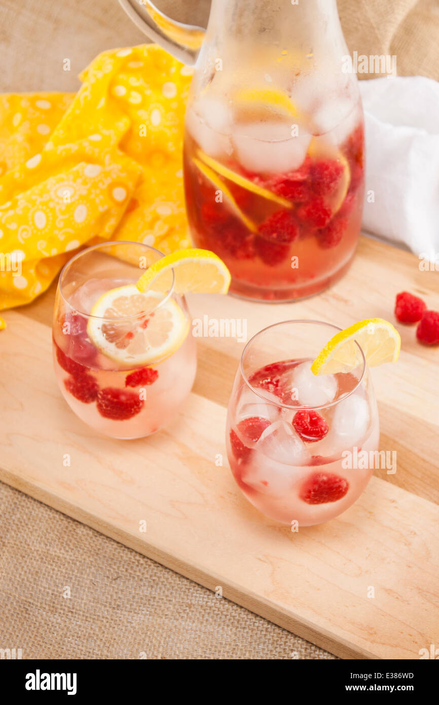 Vino bianco sangria in bicchieri con lamponi e spicchi di limone. Foto Stock