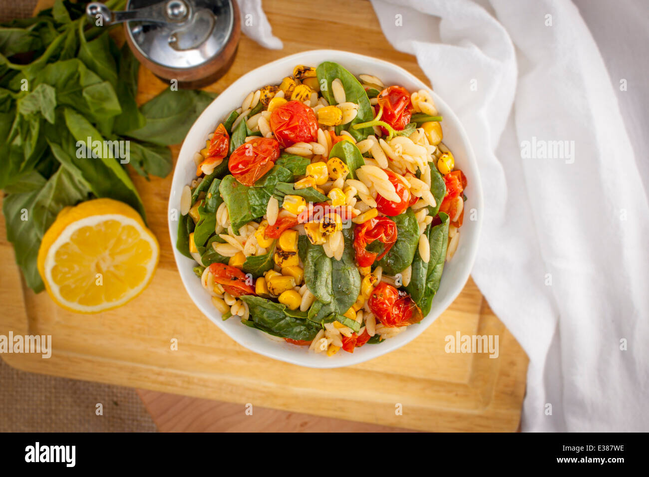 Insalata di orzo con spinaci e pomodori su un tagliere con contorni Foto Stock