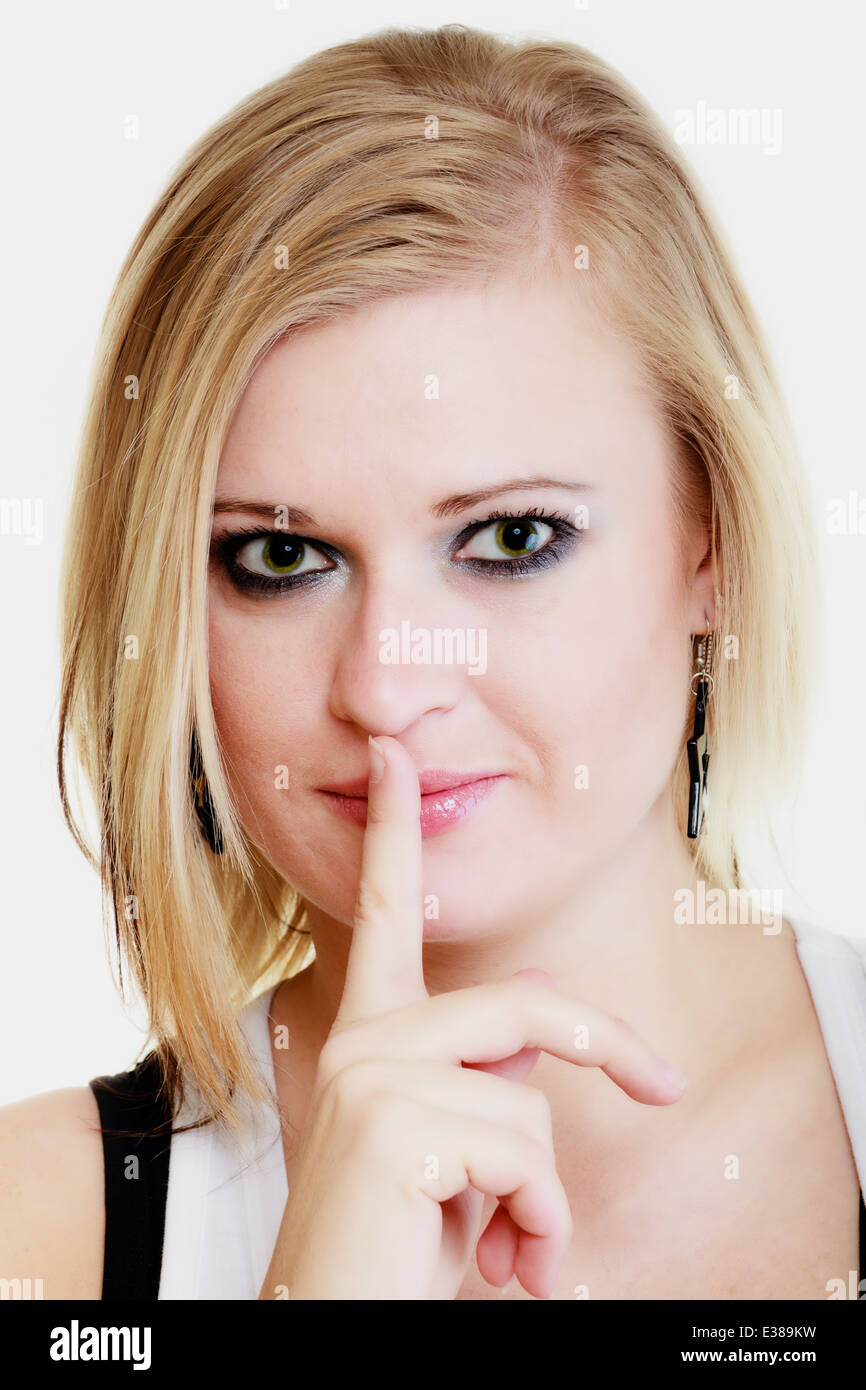 Il linguaggio del corpo. Ritratto di ragazza bionda con il dito sulle labbra per chiedere il silenzio o la segretezza hush mano gesto isolato su bianco. Foto Stock