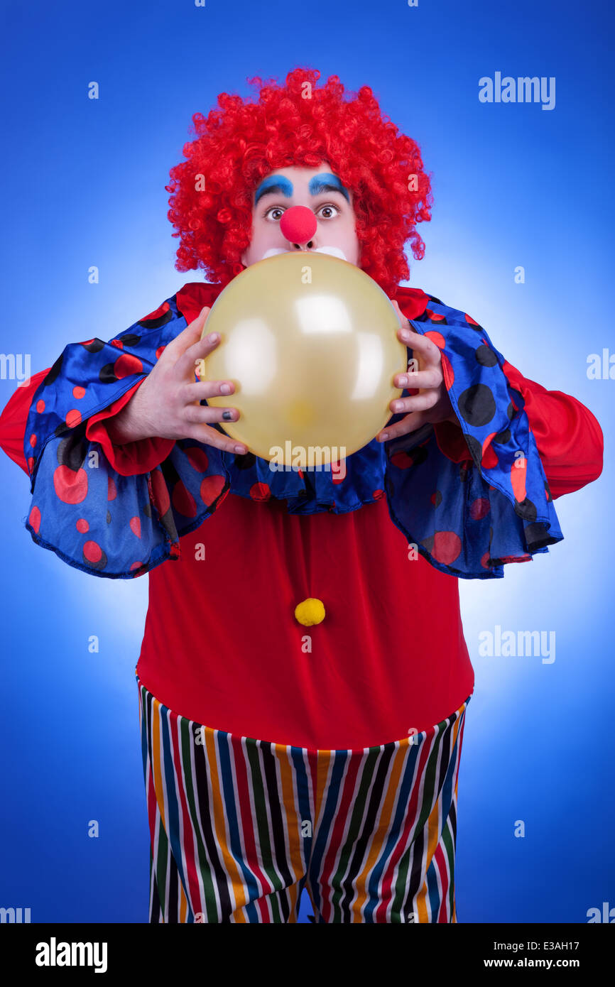 Clown con un ballon in mani su sfondo blu. Illuminazione Professionale. Umorismo. Il trucco. La felicità Foto Stock