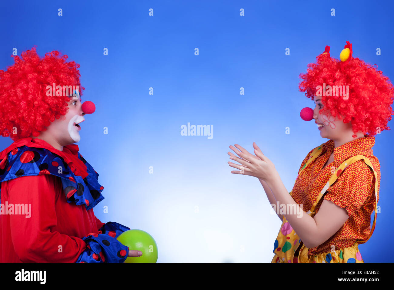Clown giovane giocando con un ballon su sfondo blu. Studio di illuminazione professionale. Colori vividi Foto Stock