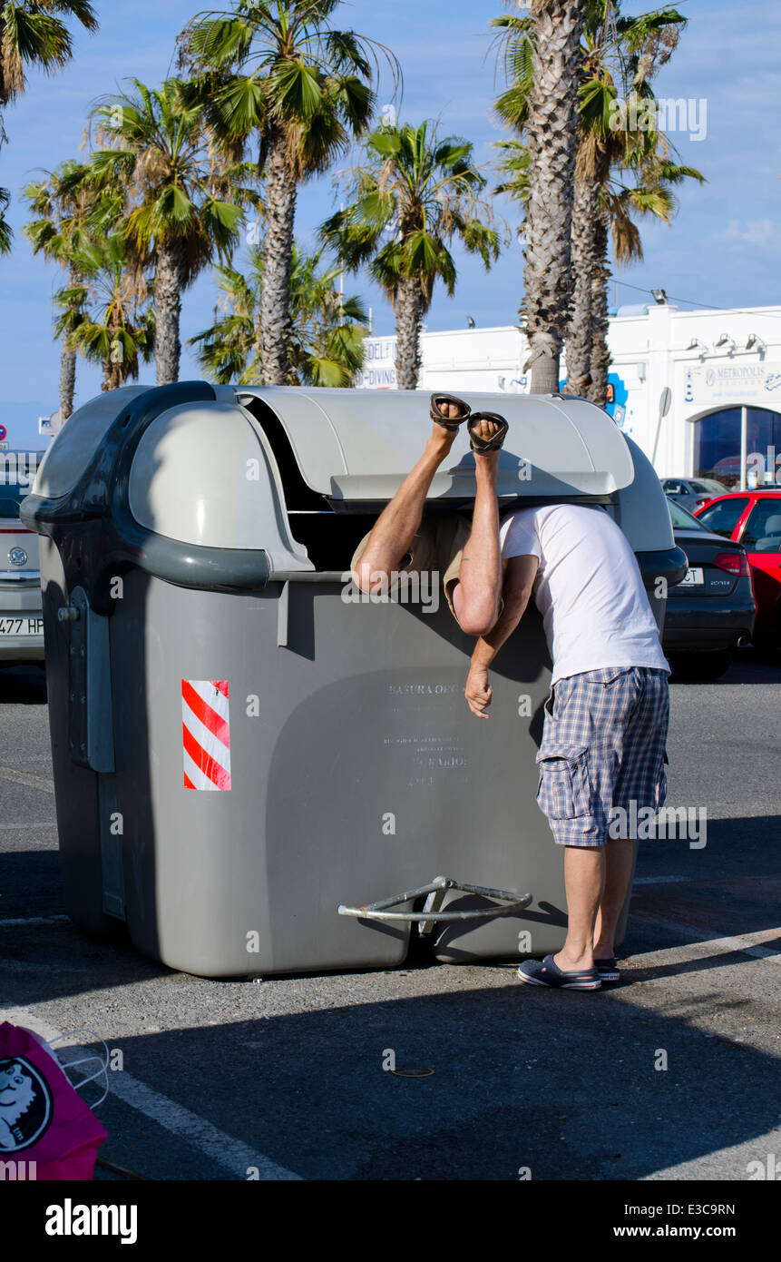 Due uomini la ricerca all'interno di uno scomparto carbage contenitore di rifiuti. Spagna. Foto Stock