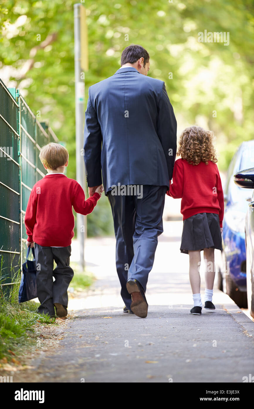 Padre andare a scuola a piedi con i bambini sulla strada per il lavoro Foto Stock