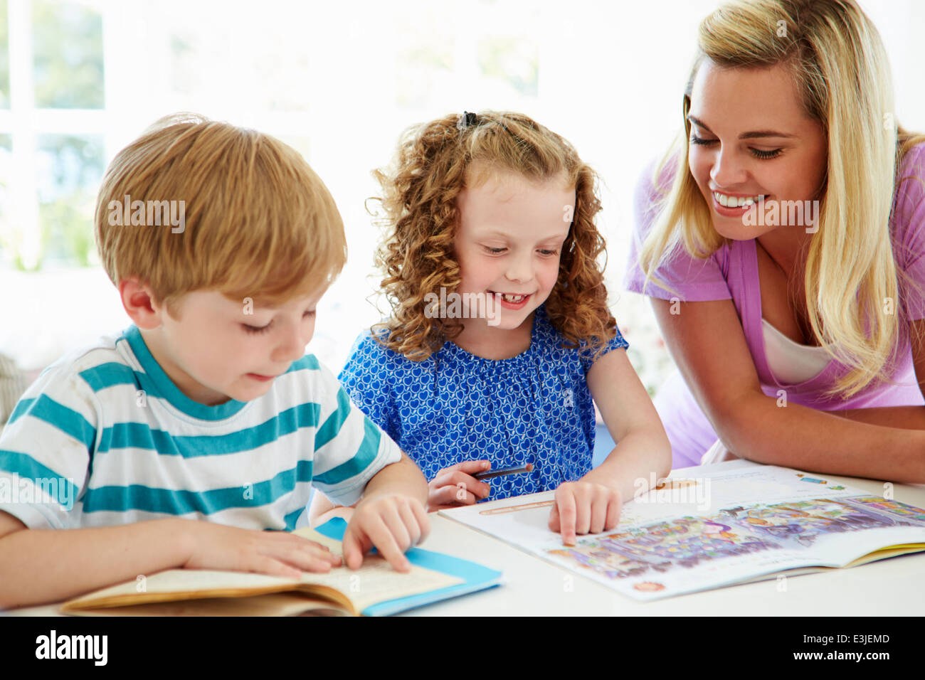 Madre aiutando i bambini con i compiti in cucina Foto Stock