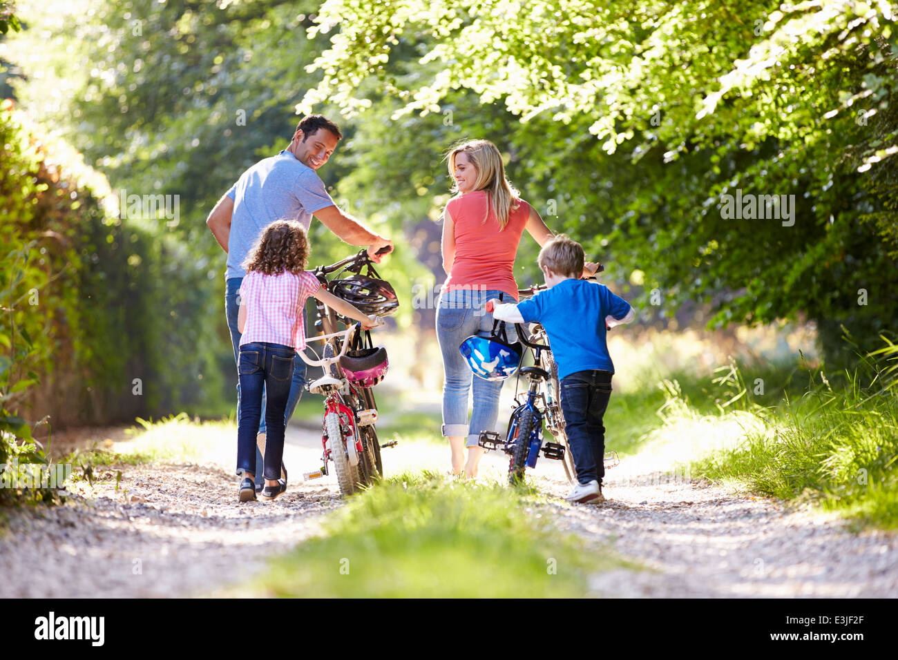Famiglia spingendo le moto lungo il paese via Foto Stock