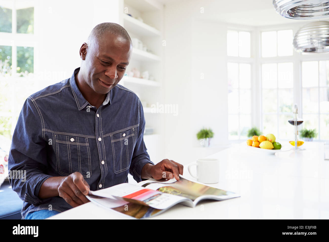 African American uomo rivista di lettura a casa Foto Stock