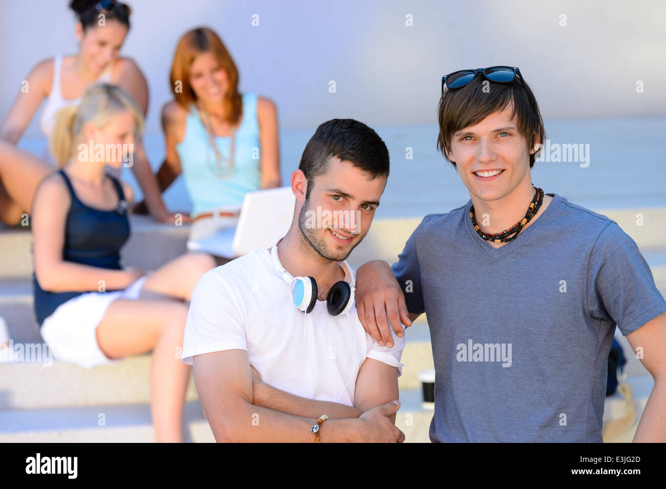 Due ragazzi dello studente in piedi al di fuori del college summer amici in background Foto Stock