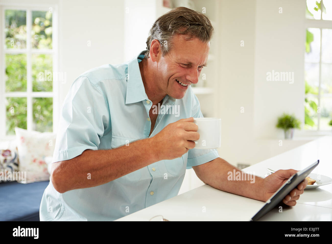 Uomo di mezza età con tavoletta digitale oltre la prima colazione Foto Stock