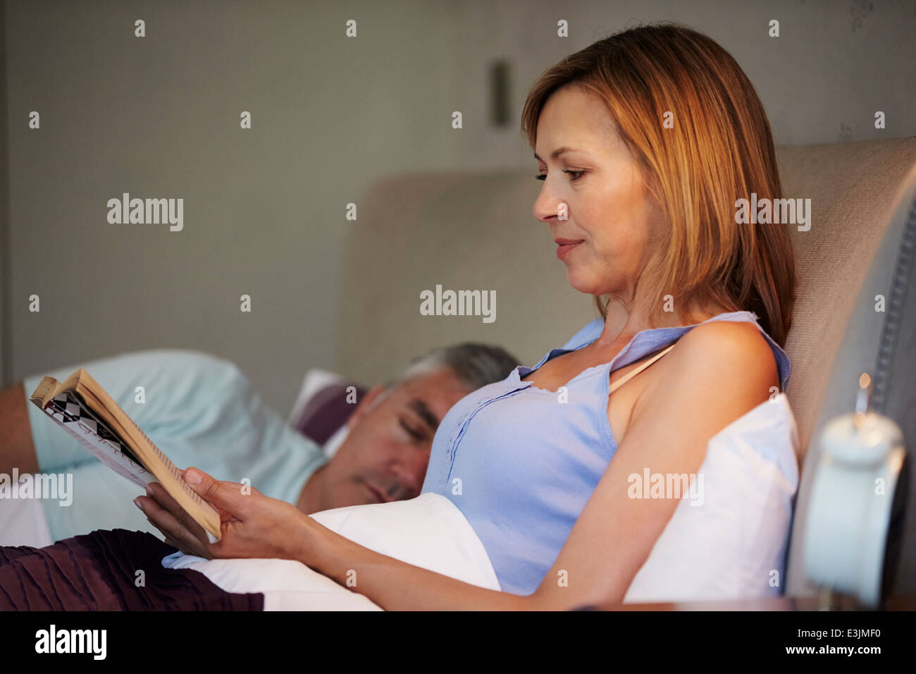 Coppia di mezza età a letto insieme con la donna Libro di lettura Foto Stock