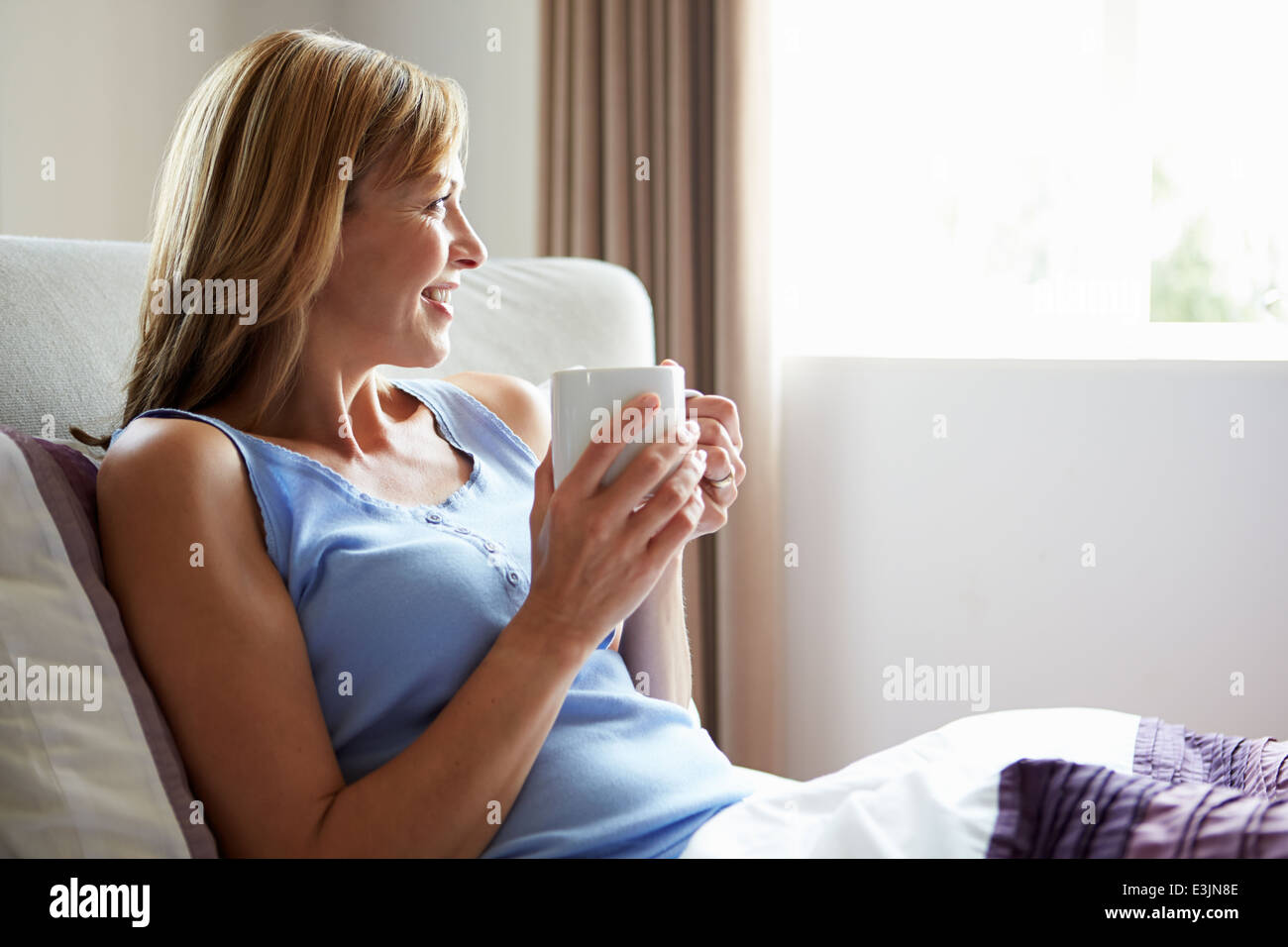 Persone di mezza età relax nel letto con bevanda calda Foto Stock