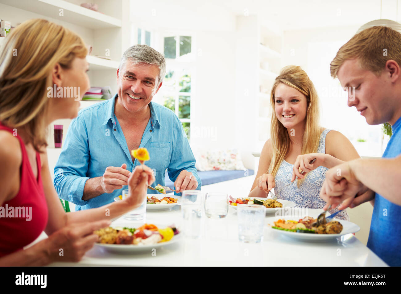 Famiglia con figli adolescenti mangiare pasto a casa insieme Foto Stock