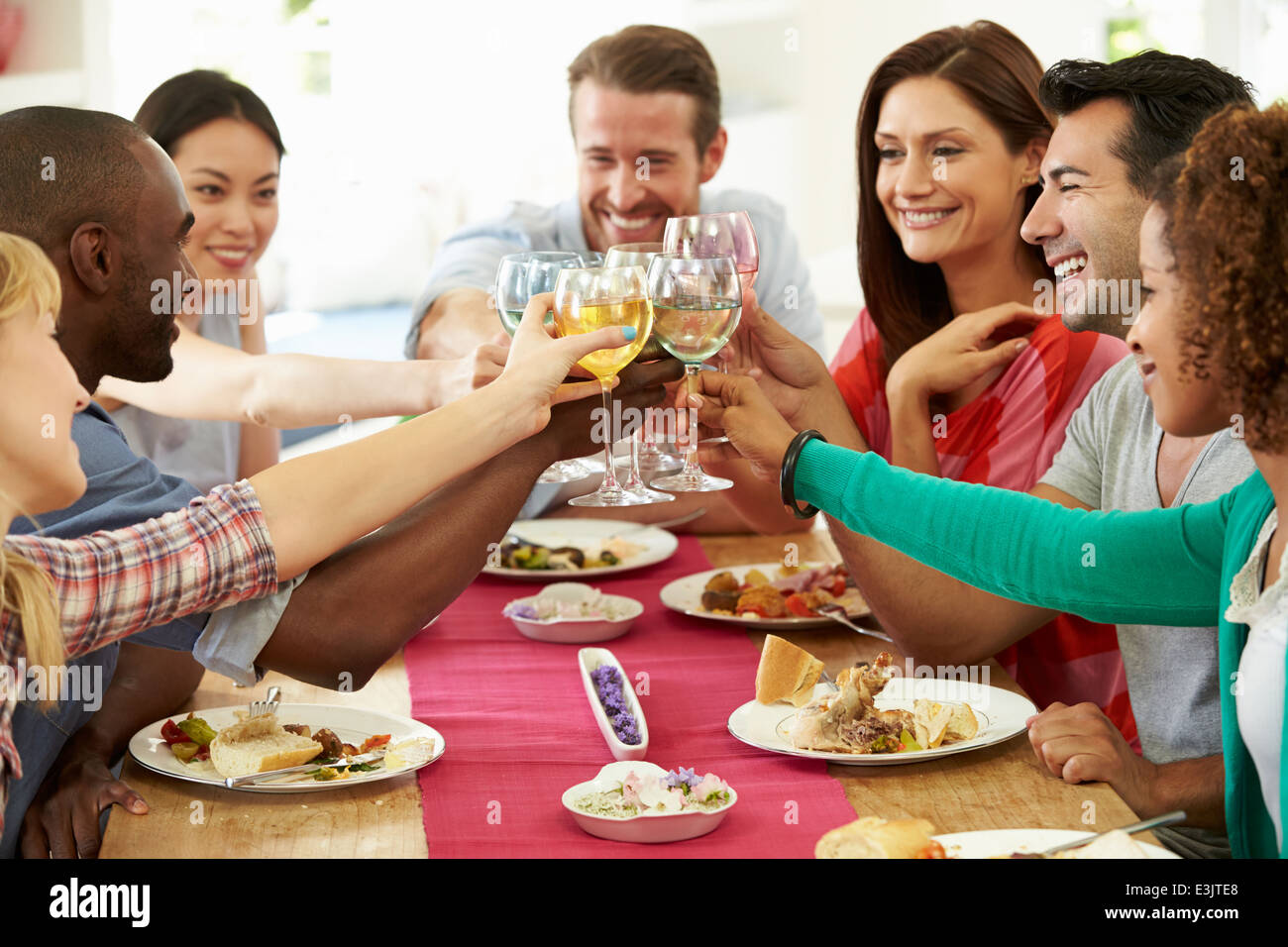 Gruppo di amici fare Toast intorno al tavolo a cena Foto Stock