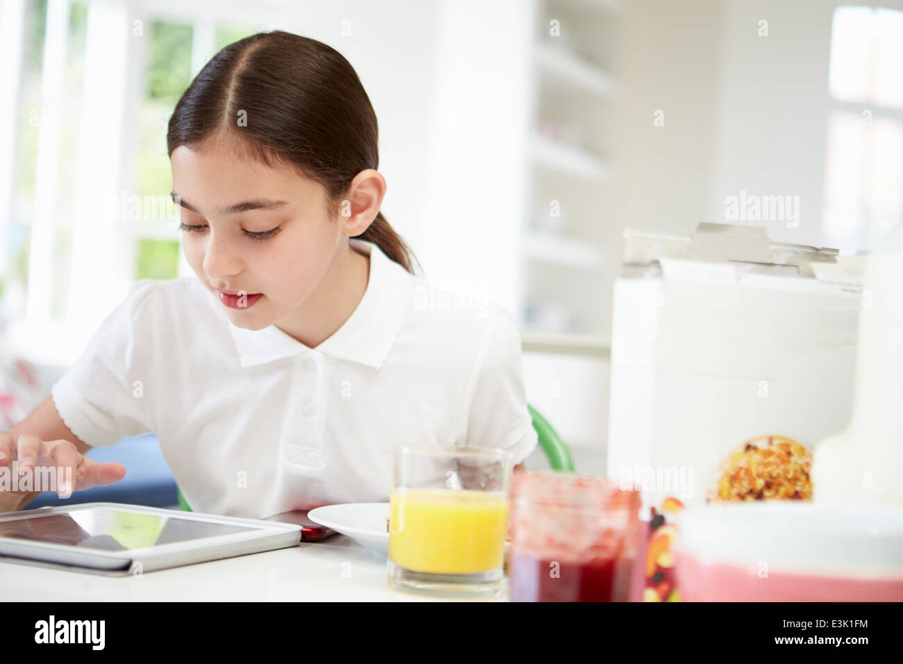 Schoolgirl con tavoletta digitale a colazione Foto Stock