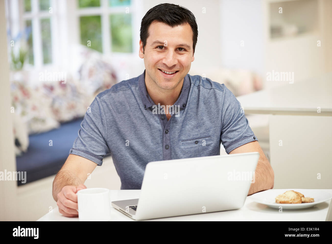 Uomo ispanico utilizzando laptop in cucina a casa Foto Stock