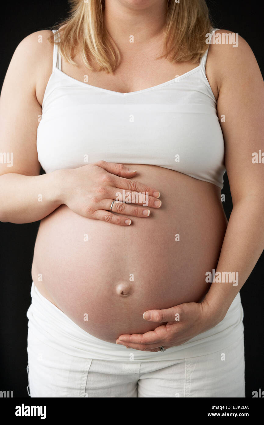 Close up ritratto di donna incinta su sfondo nero Foto Stock