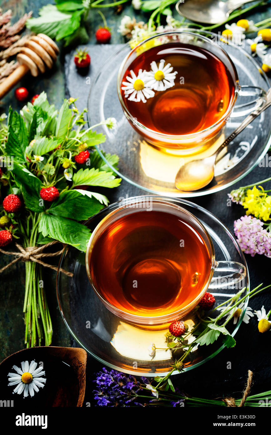 Il tè alle erbe con miele e frutti di bosco e fiori su sfondo di legno Foto Stock