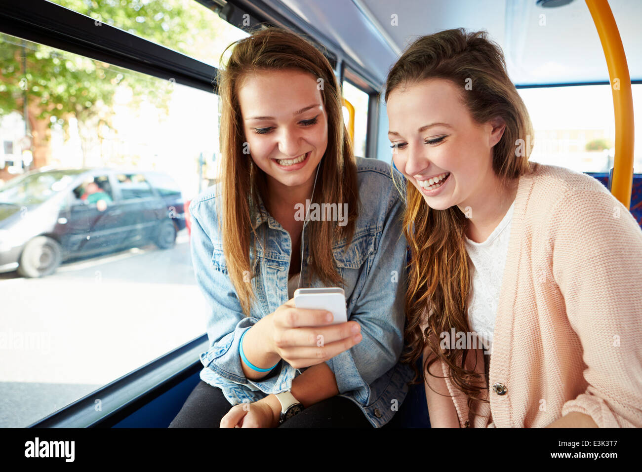 Due giovani donne la lettura di un messaggio di testo sul bus Foto Stock