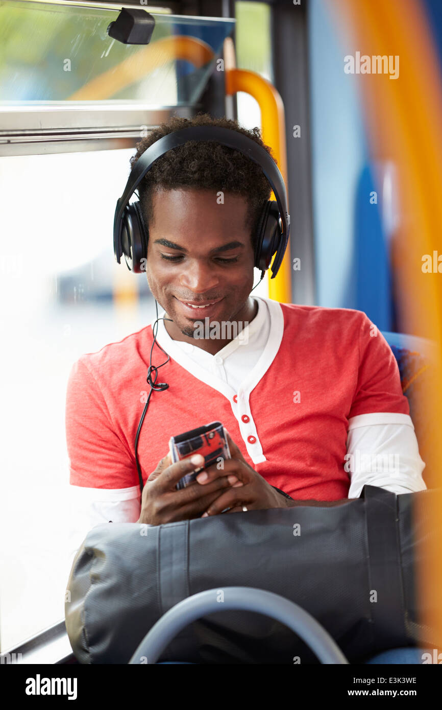 Uomo che indossa le cuffie per ascoltare musica in viaggio in autobus Foto Stock