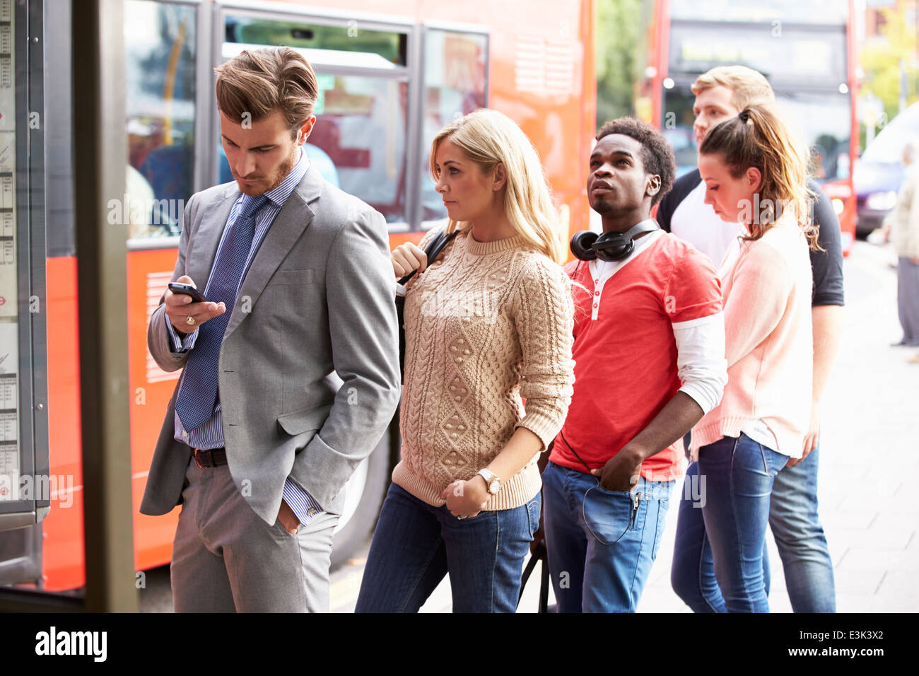 Coda di persone in attesa alla fermata del bus Foto Stock